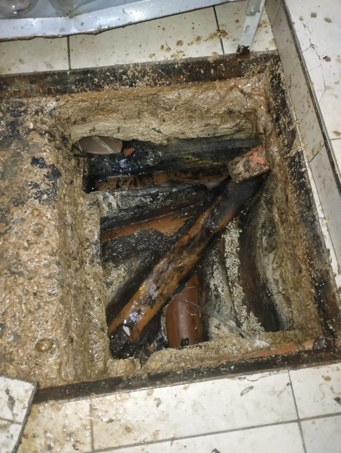 Cámara de inspección abierta con las cañerías cloacales a la vista durante una destapación