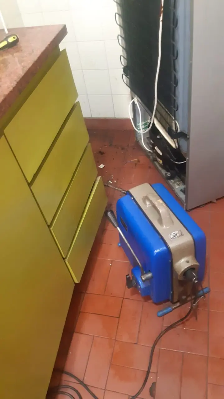 Máquina destapadora de sonda eléctrica trabajando sobre el desagüe de una cocina