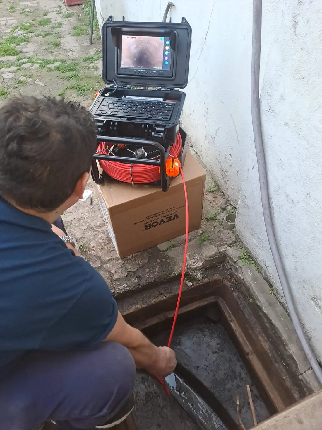 Sonda con cámara entrando a una cámara de inspección mientras la pantalla del equipo muestra el interior del caño cloacal